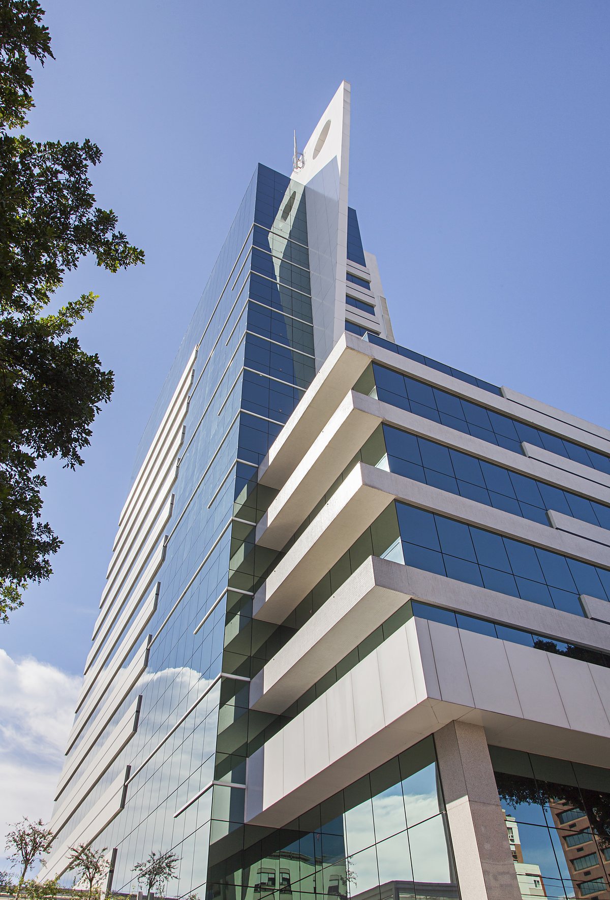 Trust Business Center em contra-plongée: fachada de vidro azul, lâmina branca da coroa e as marquises do embasamento.