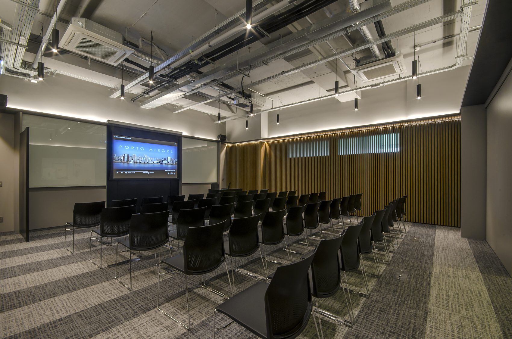 Sala multiuso vista em diagonal, com a divisória retrátil recolhida.
